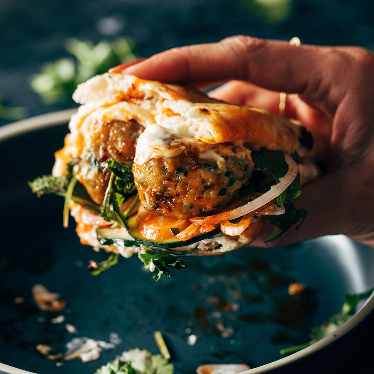 Ginger chicken meatball sandwich being held by a hand.