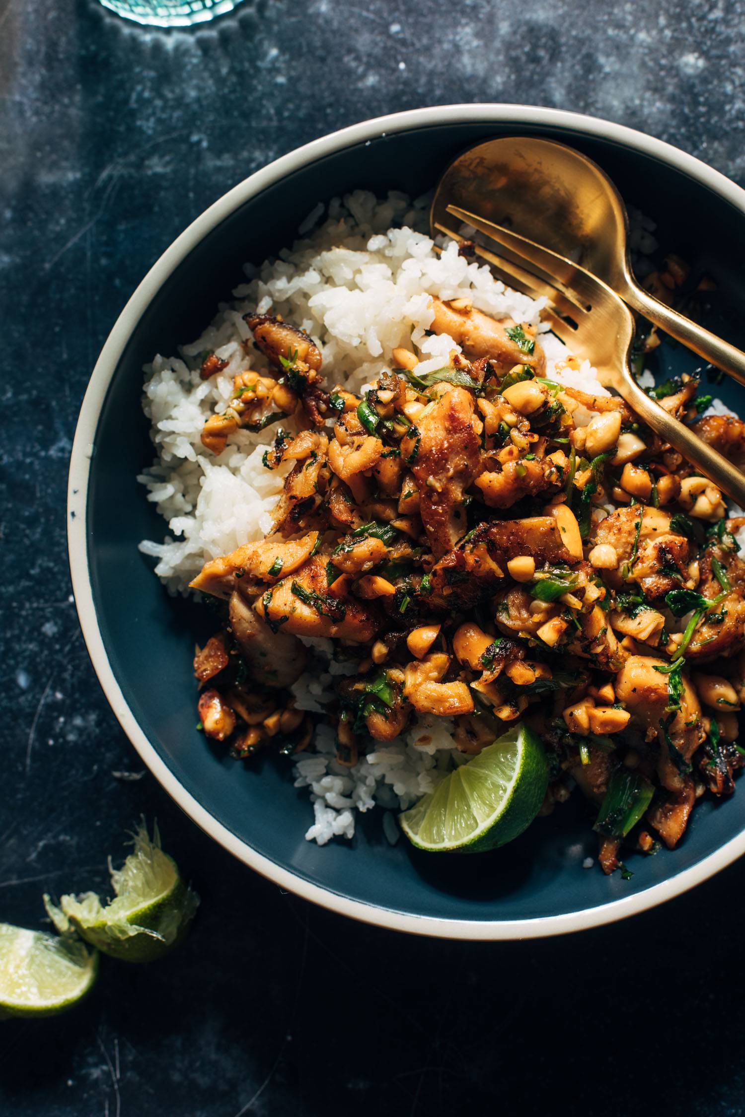 Ginger peanut chicken in a bowl with rice and a spoon and fork.