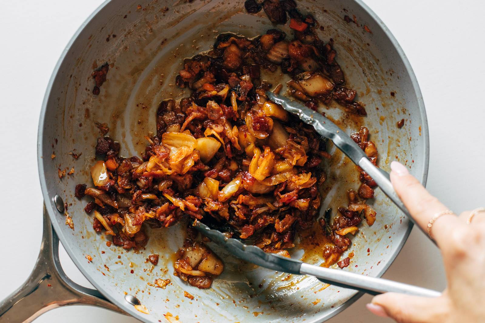 Kimchi and bacon being fried together in a pan