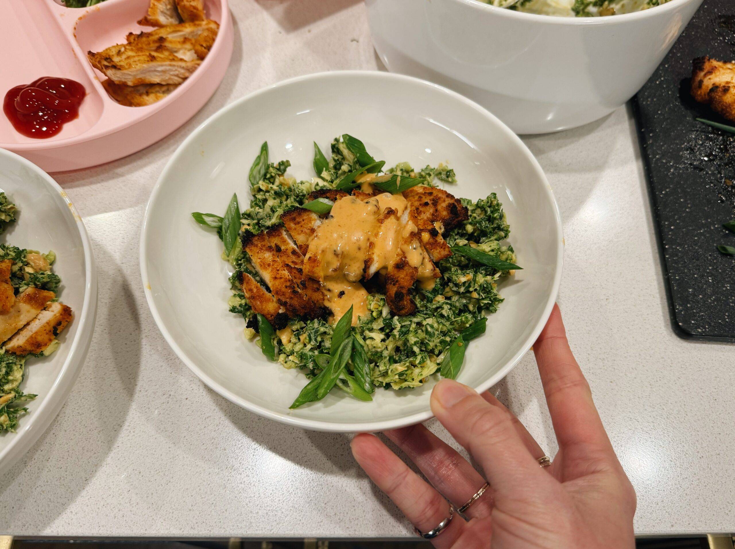 Chicken and salad in a bowl with gochujang sauce on top.