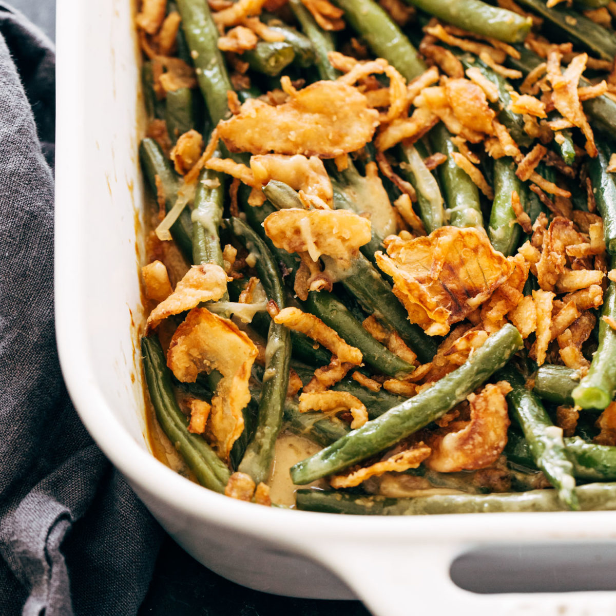 Green bean casserole in a white casserole dish with crispy fried onions on top.
