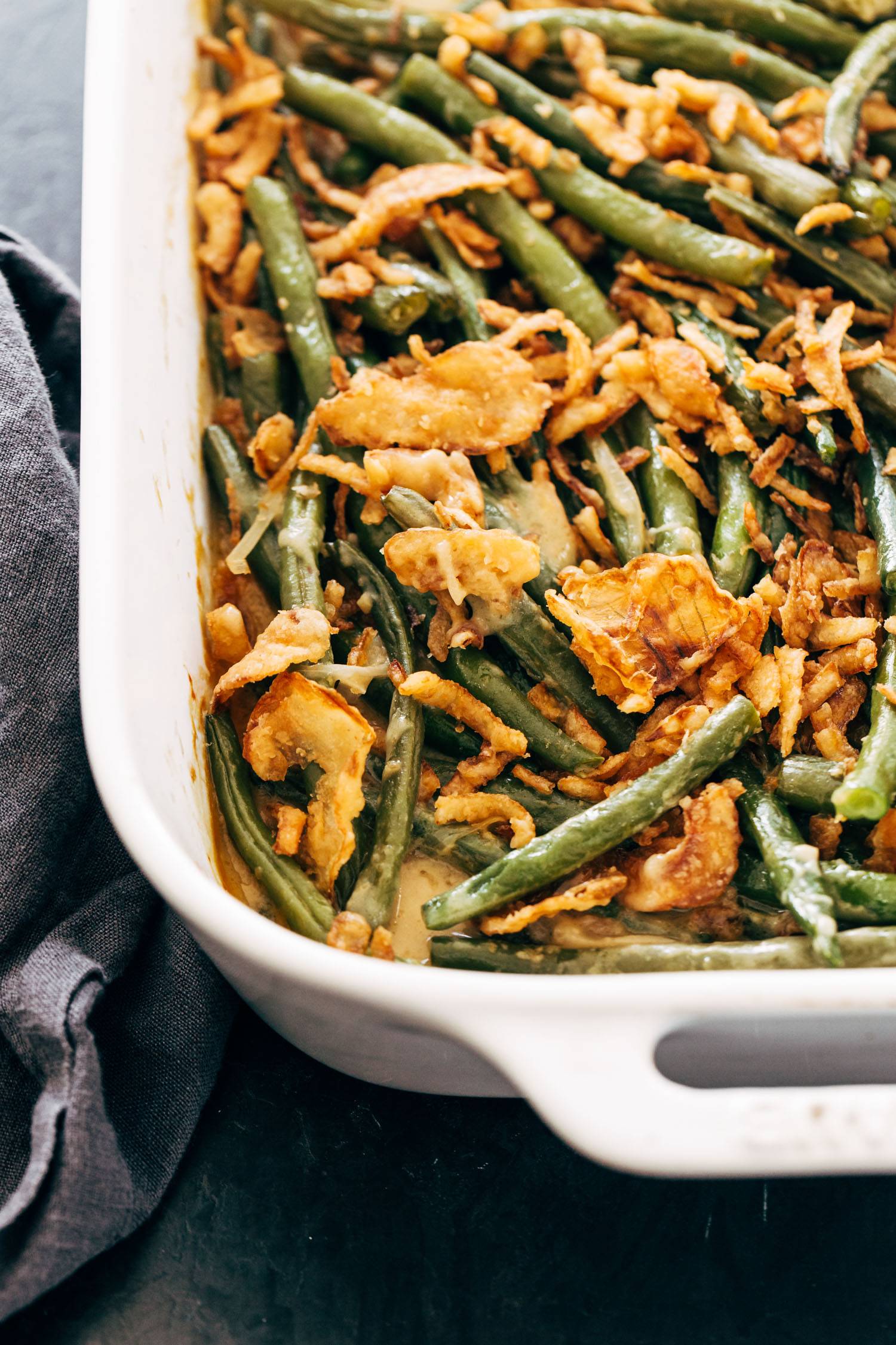 Green bean casserole in a white casserole dish with crispy fried onions on top.