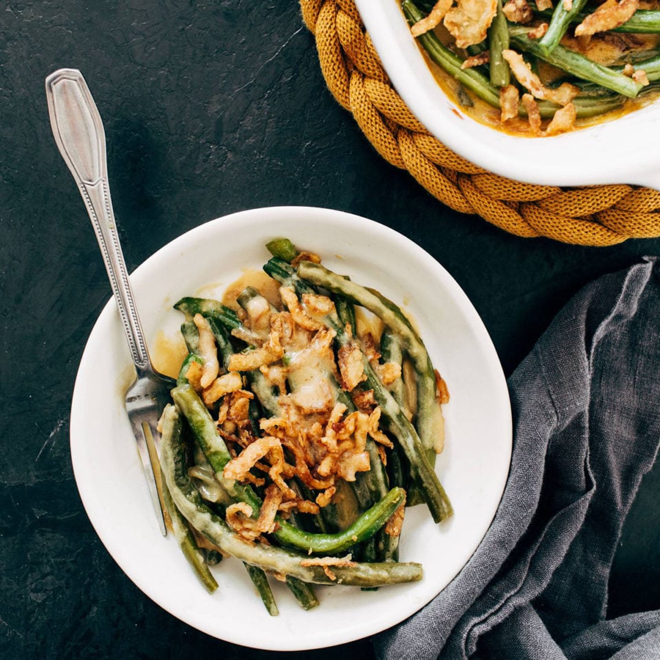 Green bean casserole on a plate with crispy onions on top.