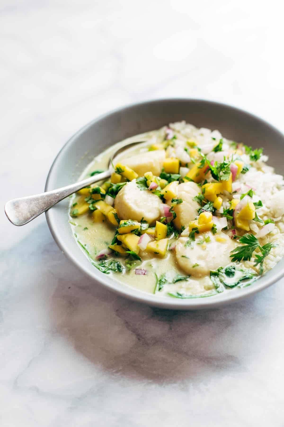 Green Curry Scallops with Mango Cilantro Salsa in a bowl with a spoon.