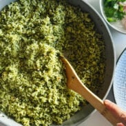 Green rice in a pan with a wooden spoon.
