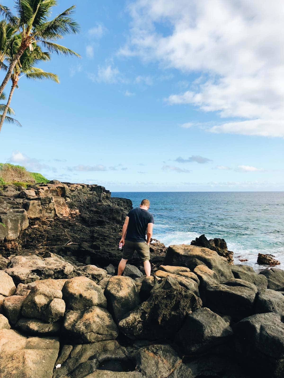 Man walking on rocks near the ocean.