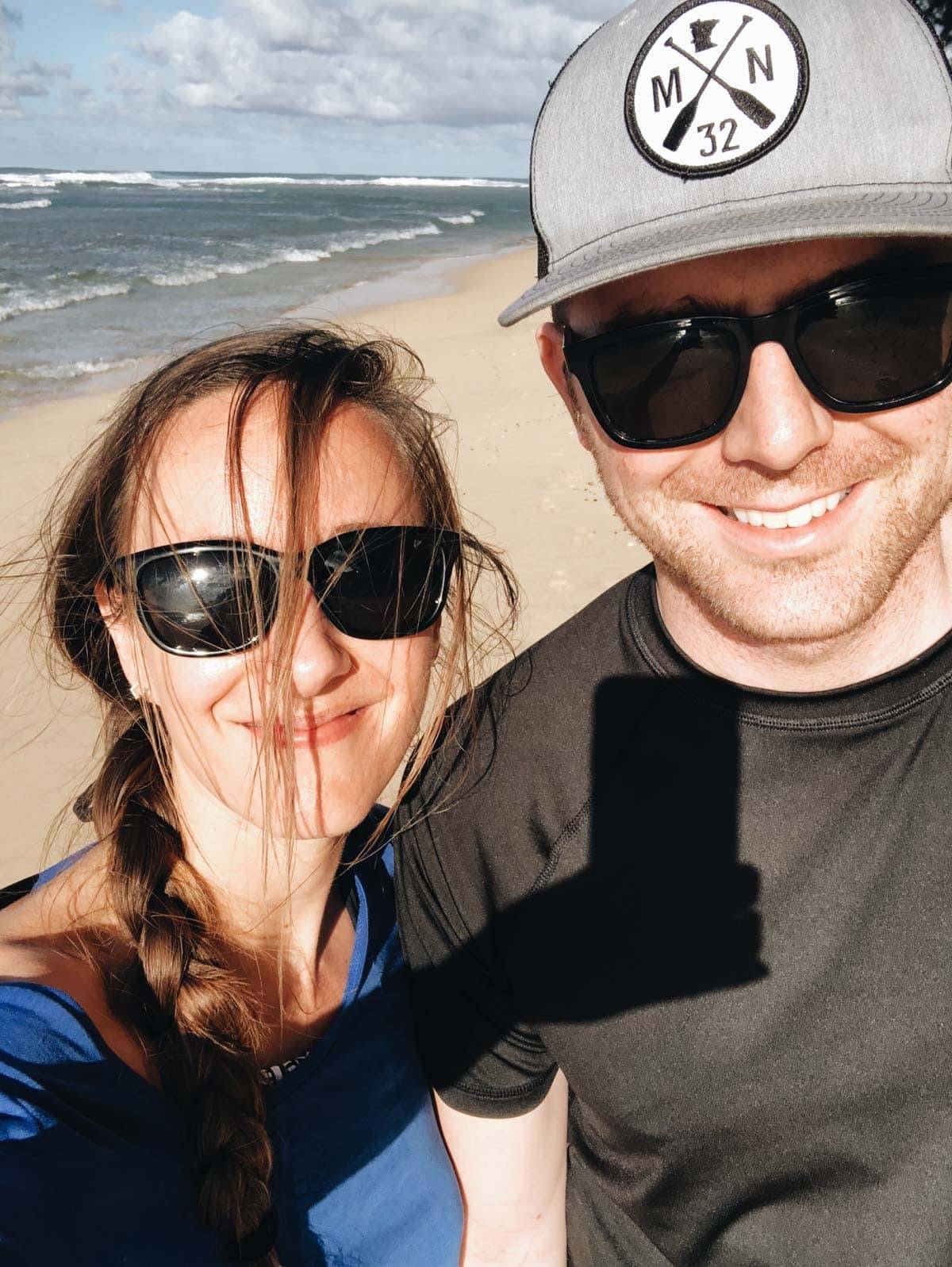 Woman and man wearing sunglasses on the beach.
