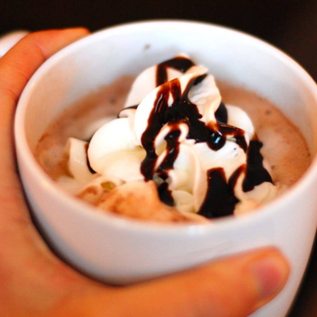 Hot Chocolate in a mug with whipped cream and chocolate syrup.
