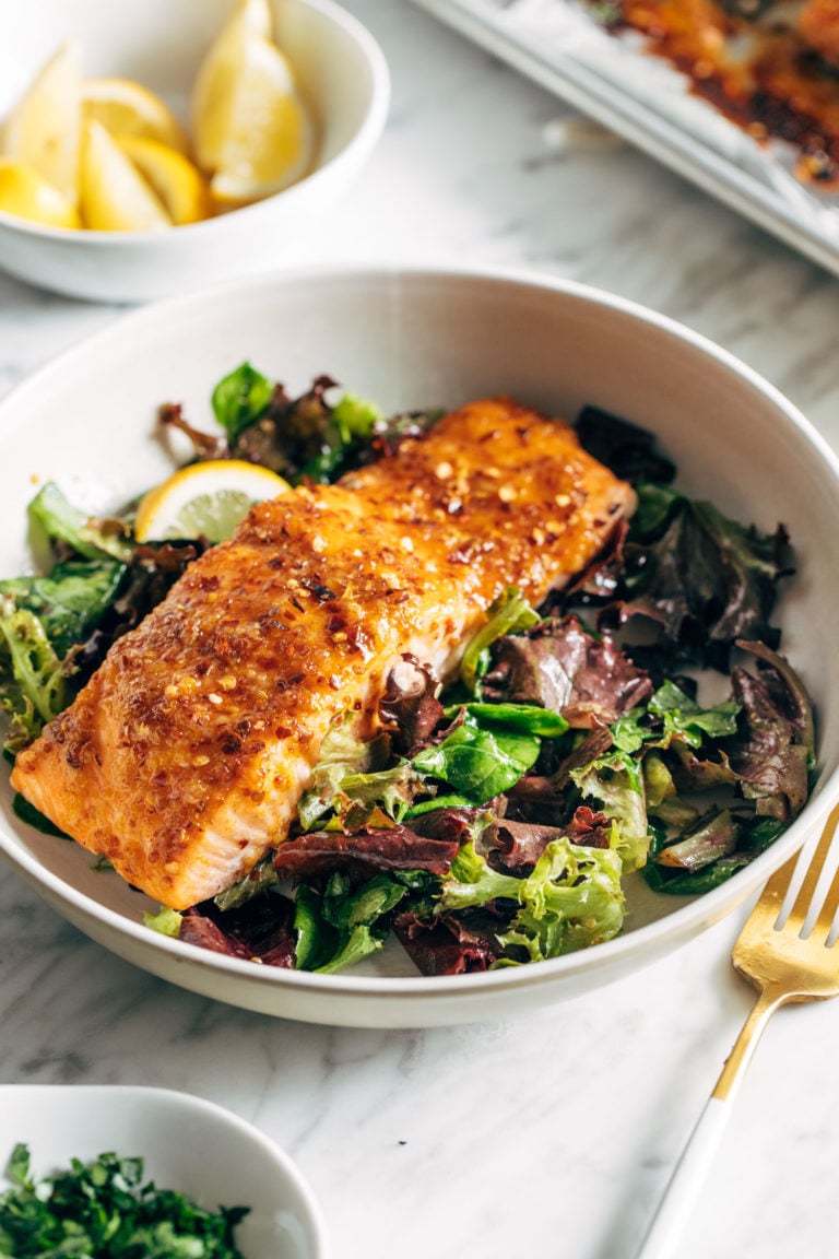 A piece of salmon sitting on a bed of greens.