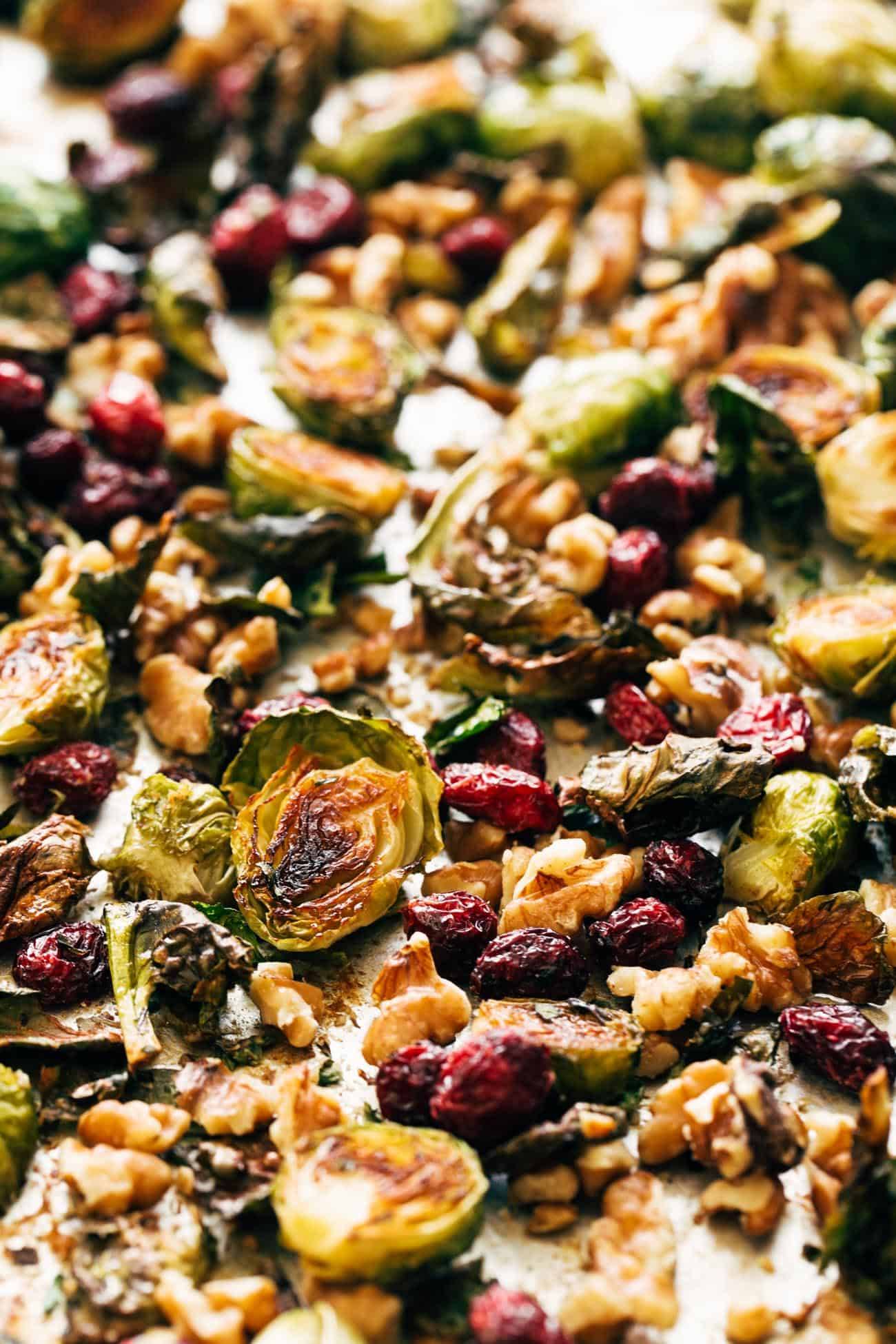 Close-up of roasted Brussels sprouts on a pan with walnuts and cranberries.