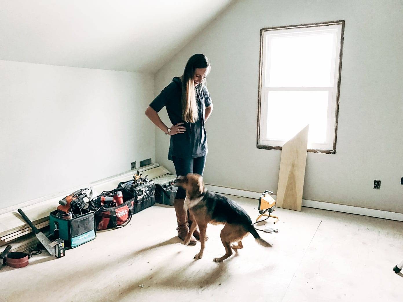 A woman looking down at a dog in front of her.