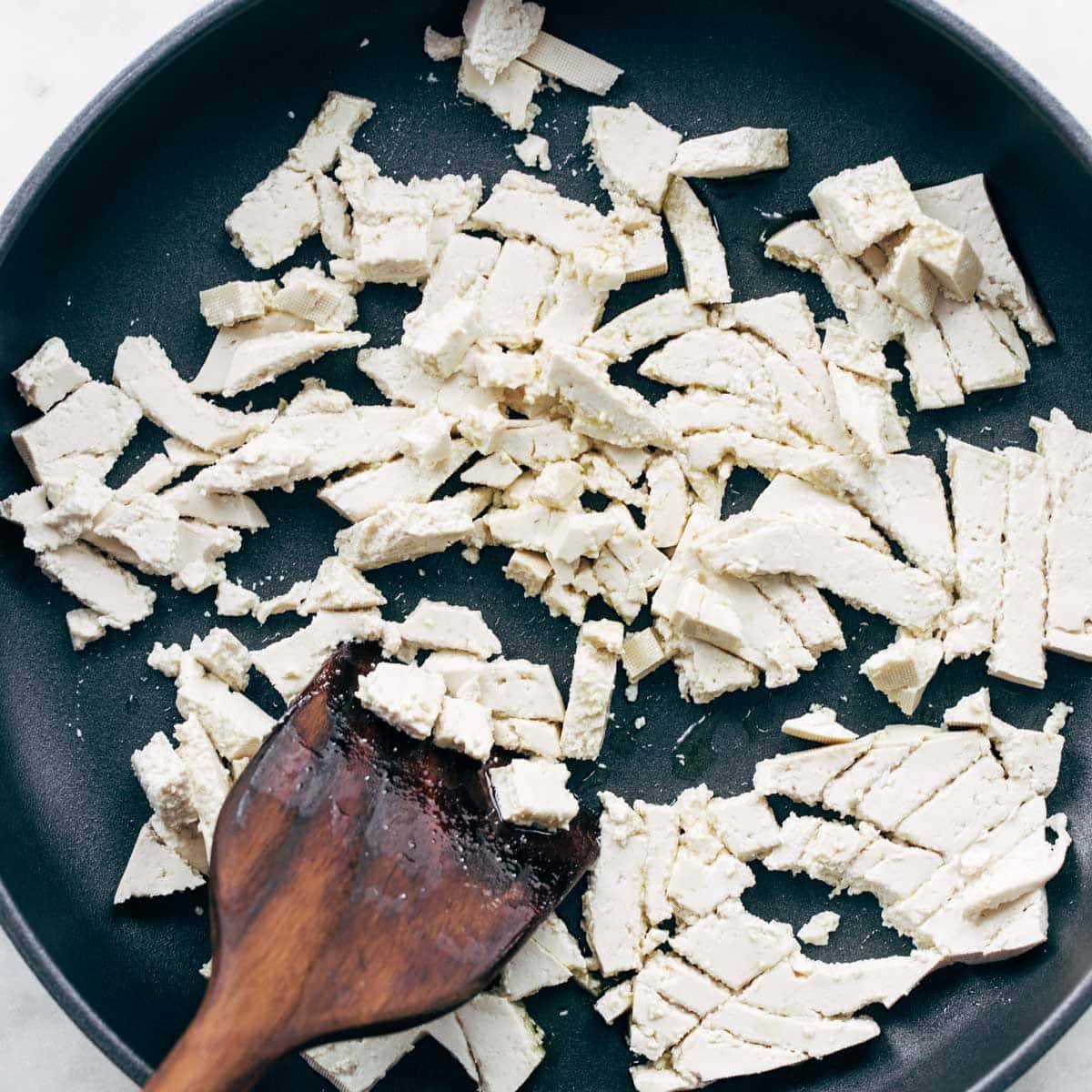 Tofu being scrambled in pan.