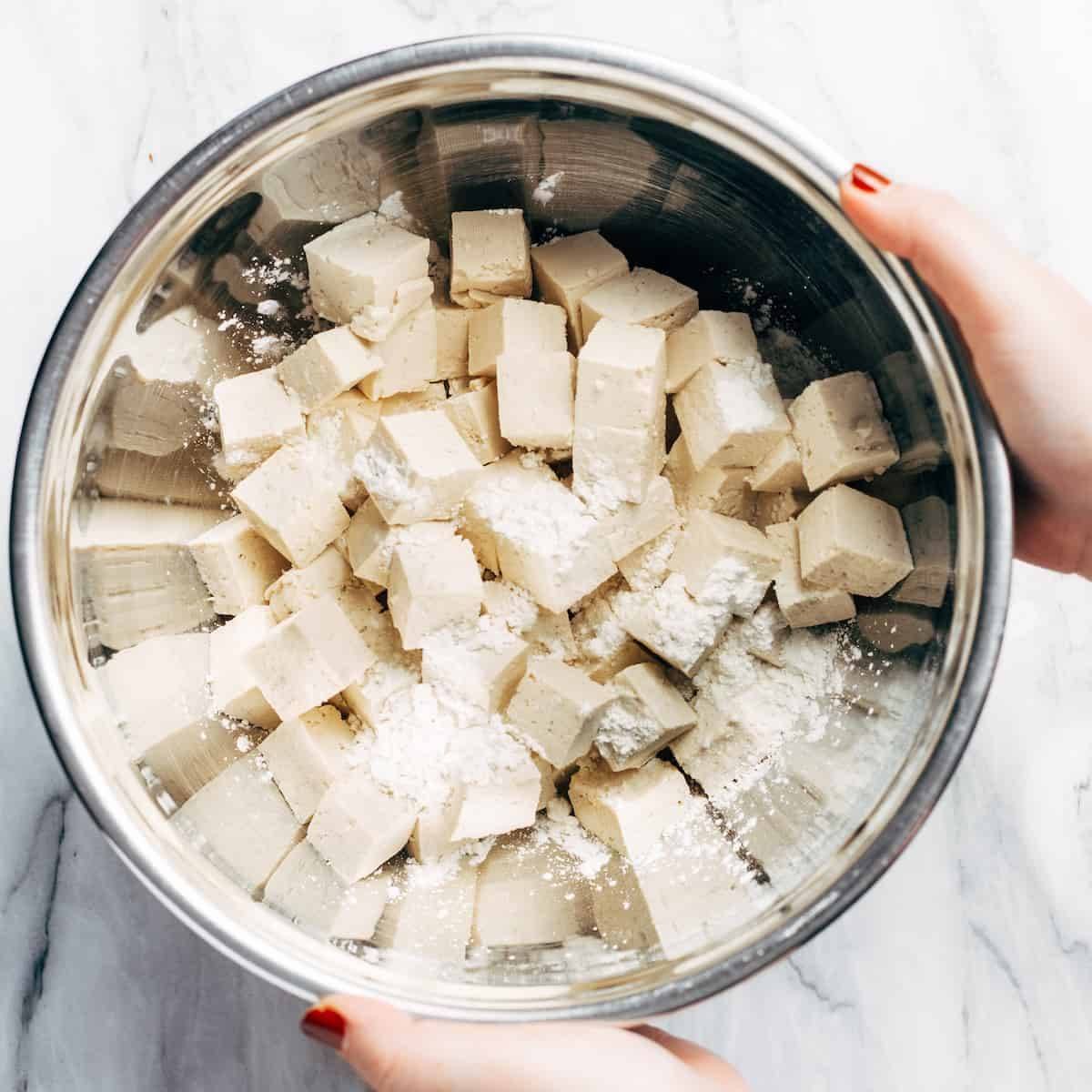 Cubed tofu egy tálban kukoricakeményítővel.