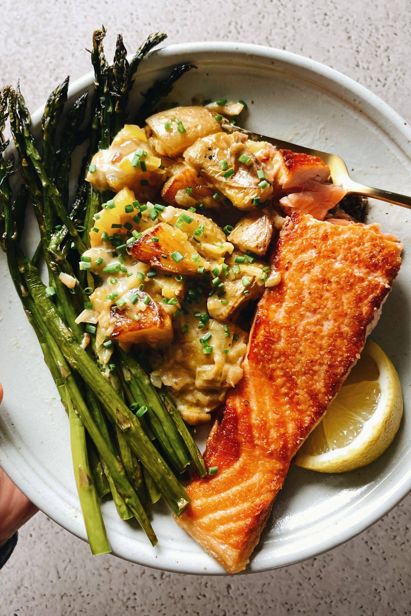 Pan-fried salmon on a plate with creamed leeks and asparagus