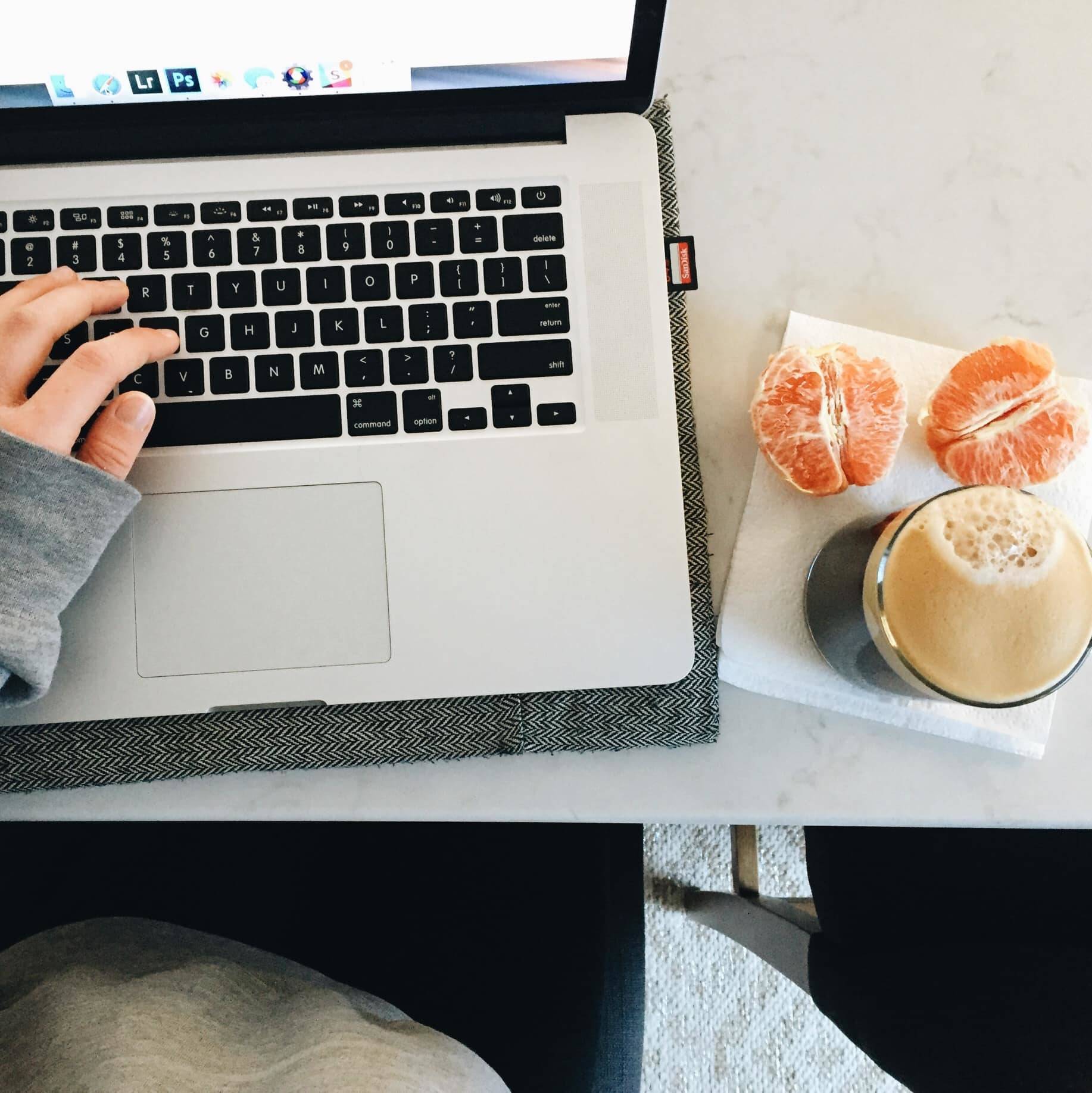 laptop with a hand and oranges with coffee