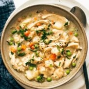 A bowl of chicken and dumplings with veggies in it.