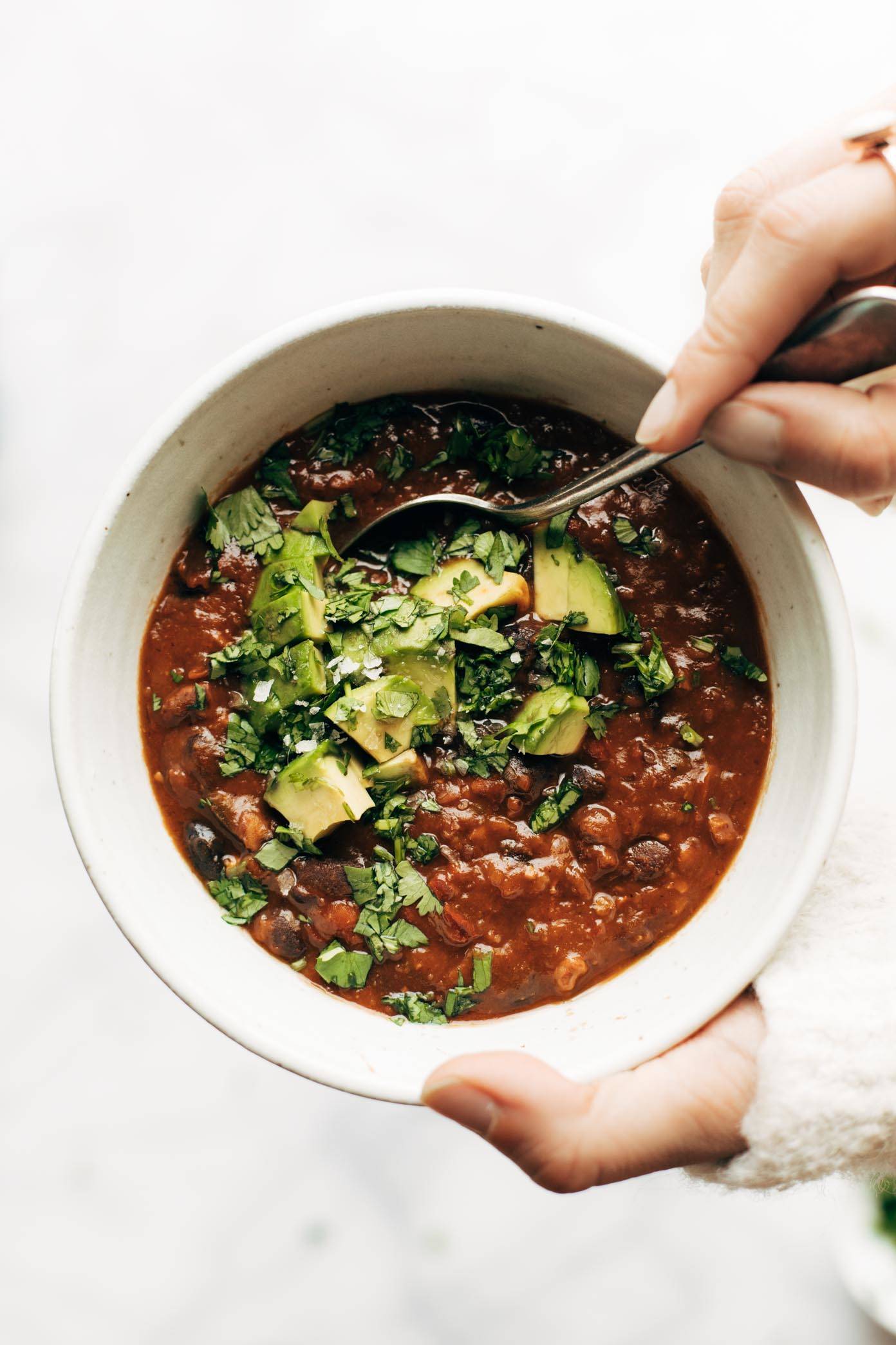 A deep white bowl of Instant Pot Chili with cilantro, and avocado on top.