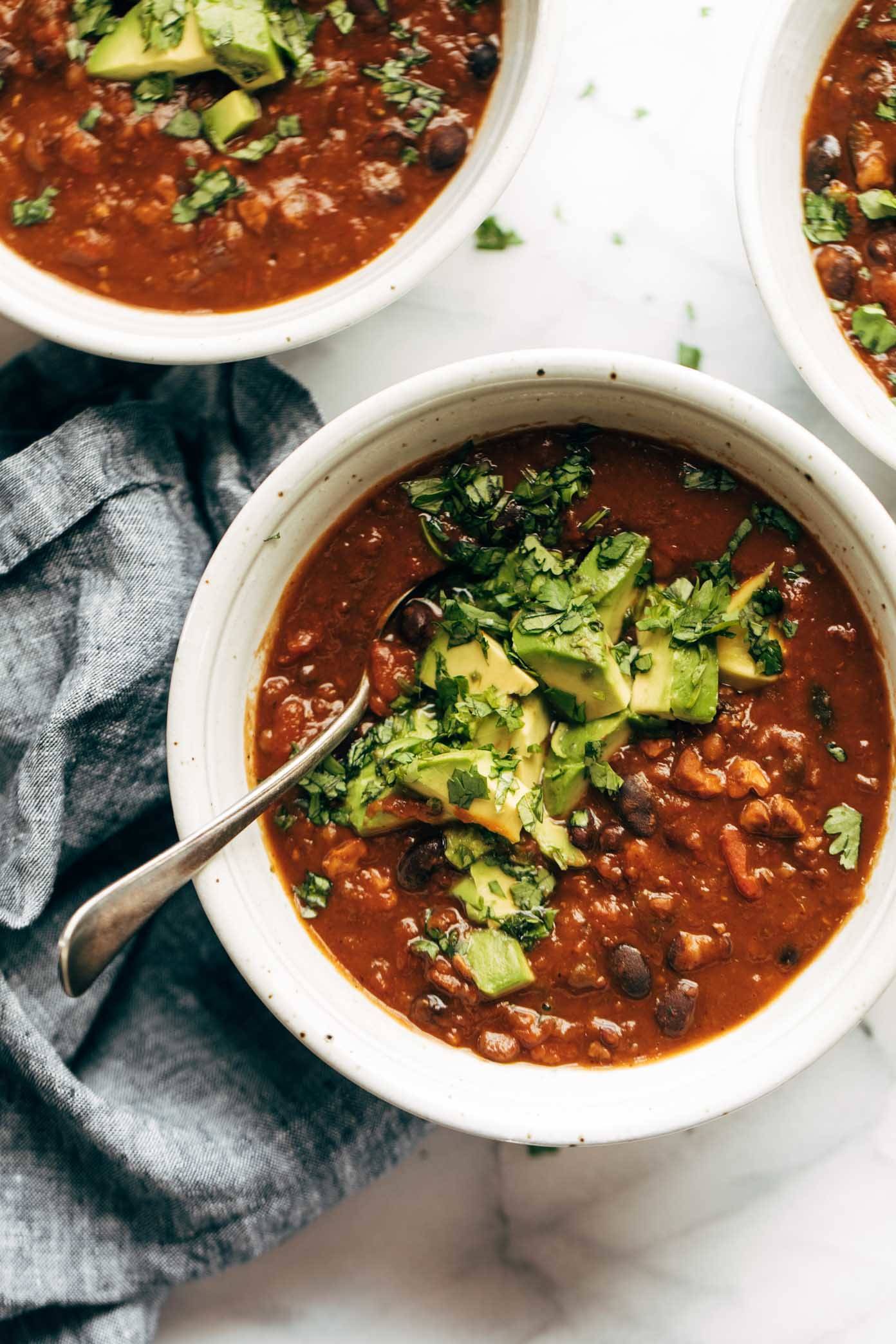 Chili in a bowl with a spoon and toppings.