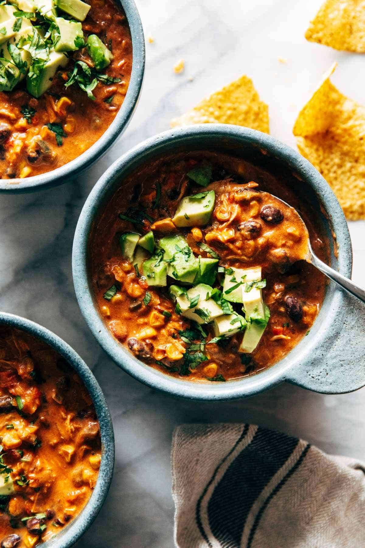 Queso chicken chili in a bowl with avocado.