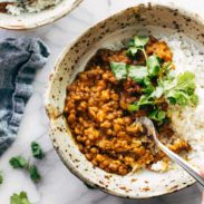 Red curry lentils with rice in a bowl with spoon.