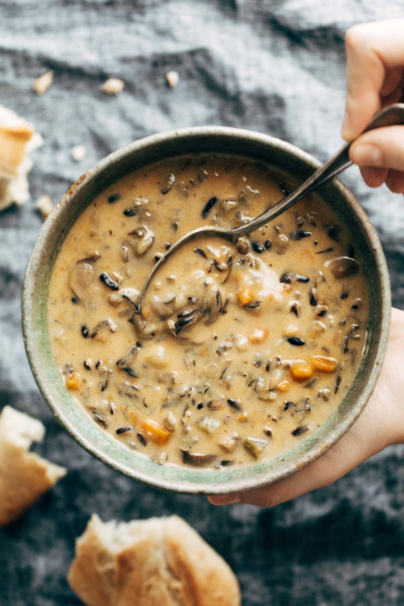 Wild Rice Soup in a bowl with a spoon and pieces of bread.