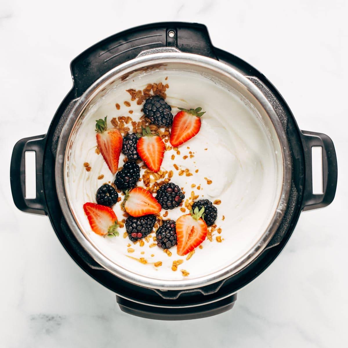 Cooked yogurt in the Instant Pot. The yogurt has berries and granola sprinkled on top. 
