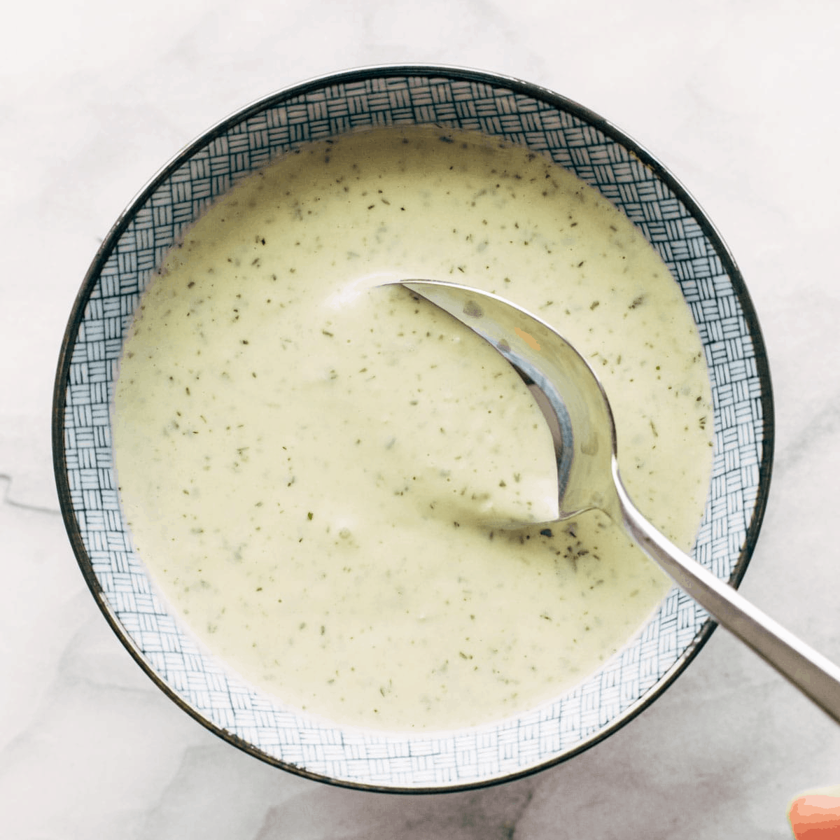 A spoon dipping into jalapeno ranch.