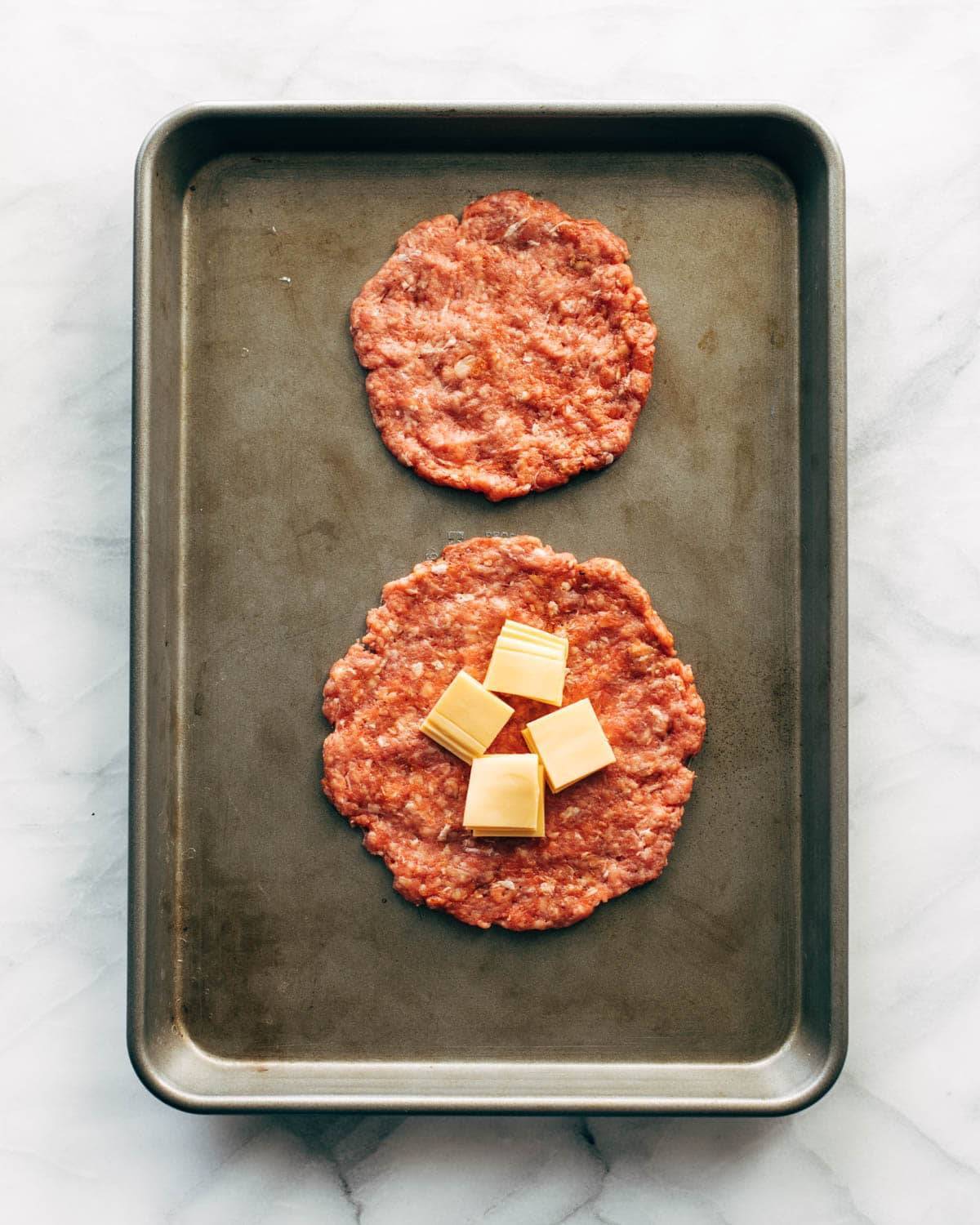 Adding cheese to two burger patties.