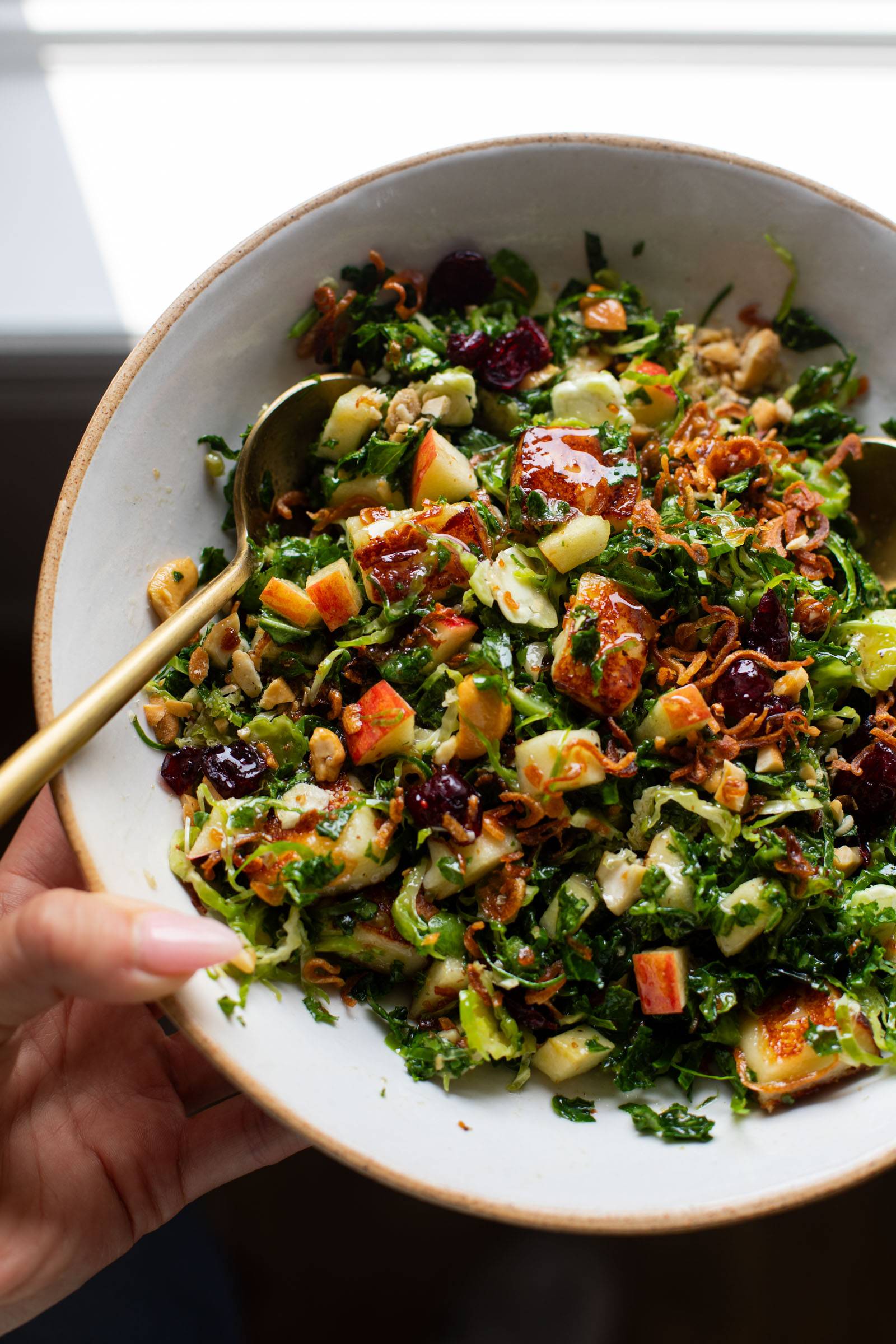 Kale apple salad in a bowl topped with crispy shallots.