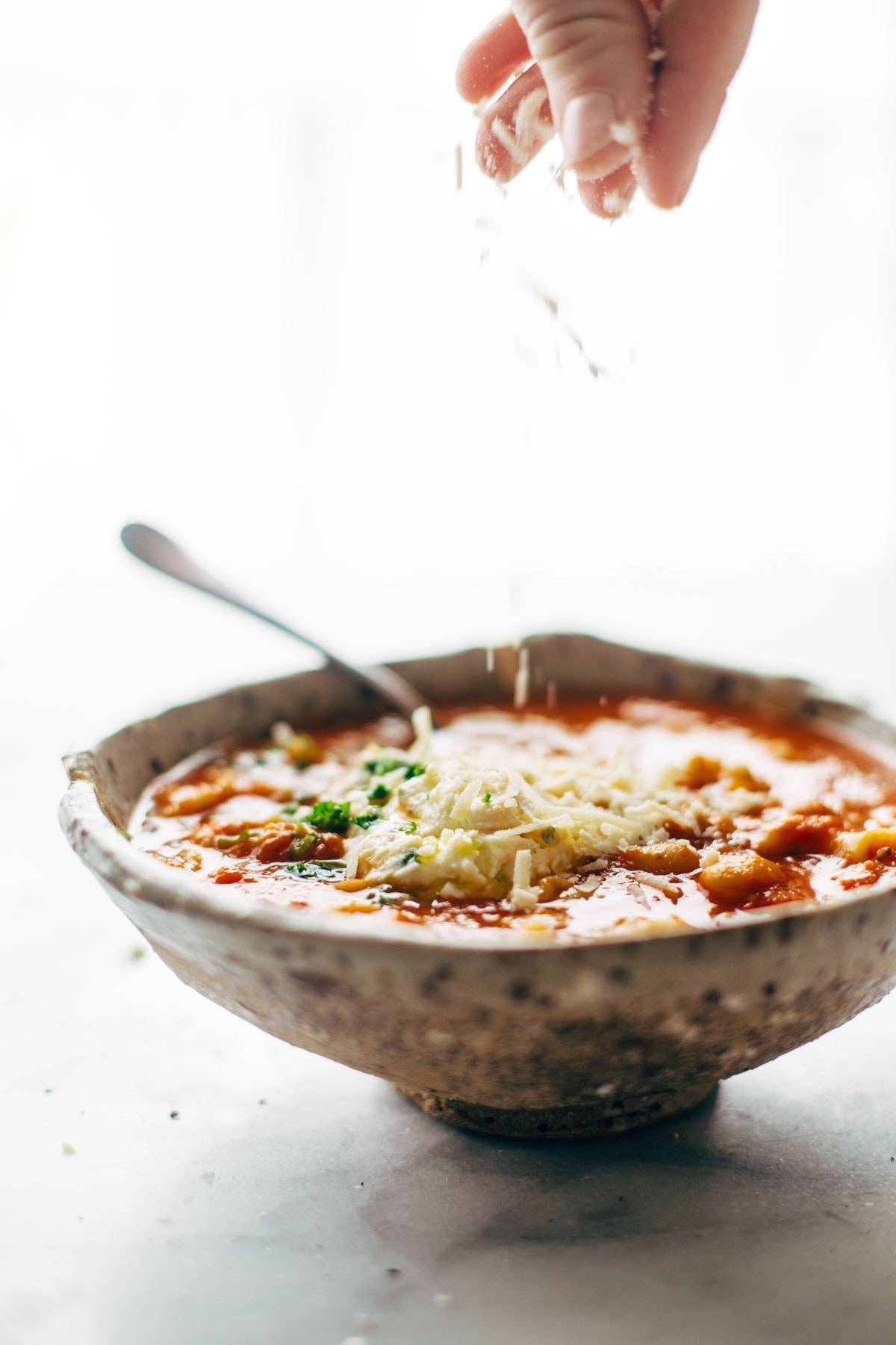 Roasted Garlic and White Bean Lasagna Soup in a speckled bowl with cheese.