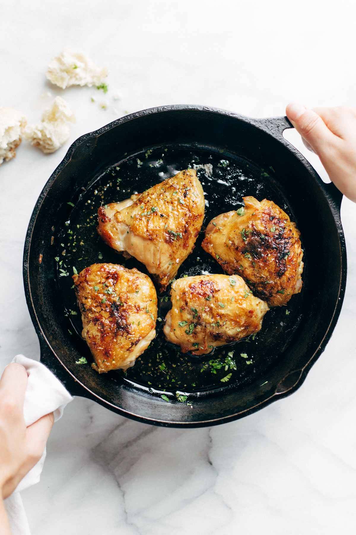 Hands holding a skillet with honey lemon chicken.