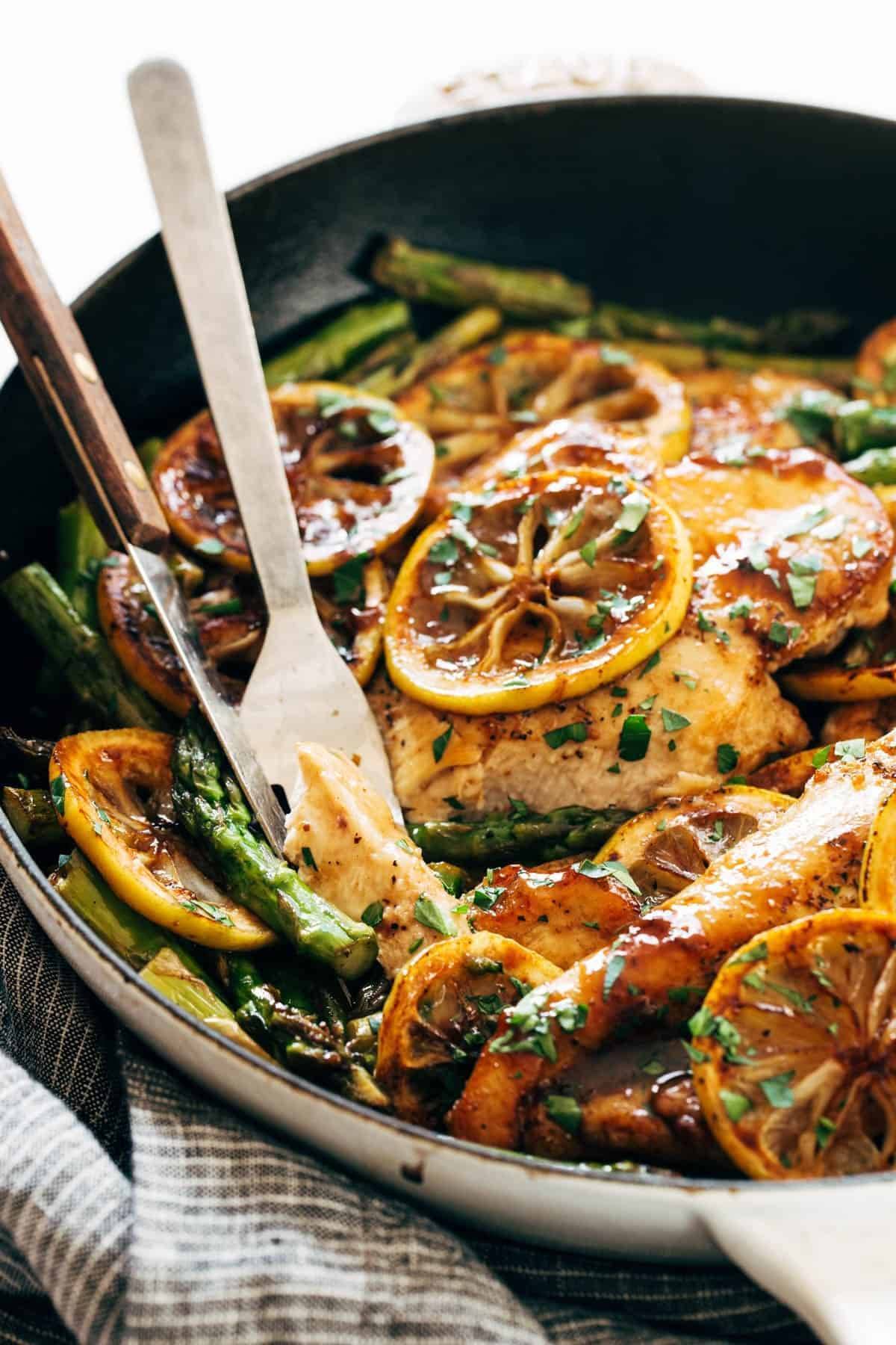 Lemon chicken with asparagus in a pan with a fork