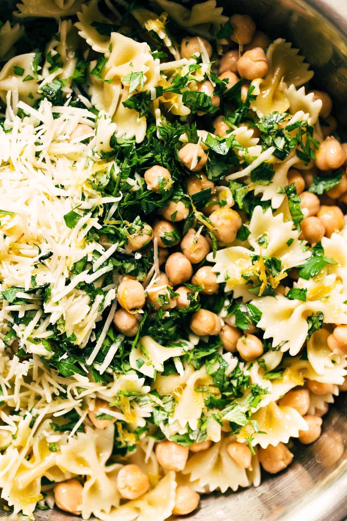 A bowl with pasta, chickpeas, herbs and cheese.