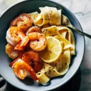 Shrimp with lemon and noodles in a bowl with a spoon.