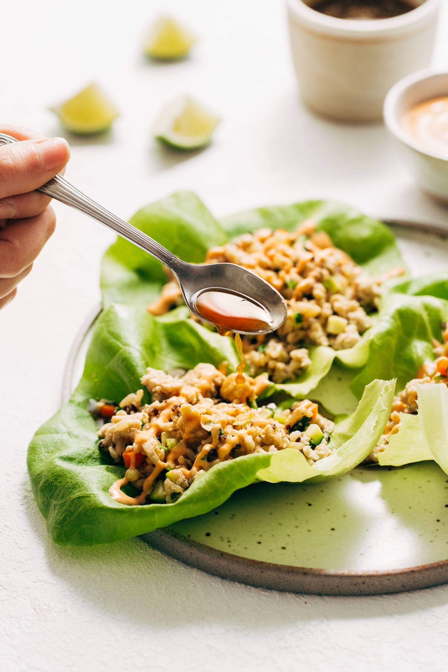 Chicken lettuce wraps on a plate with a lime drench sauce poured over the top