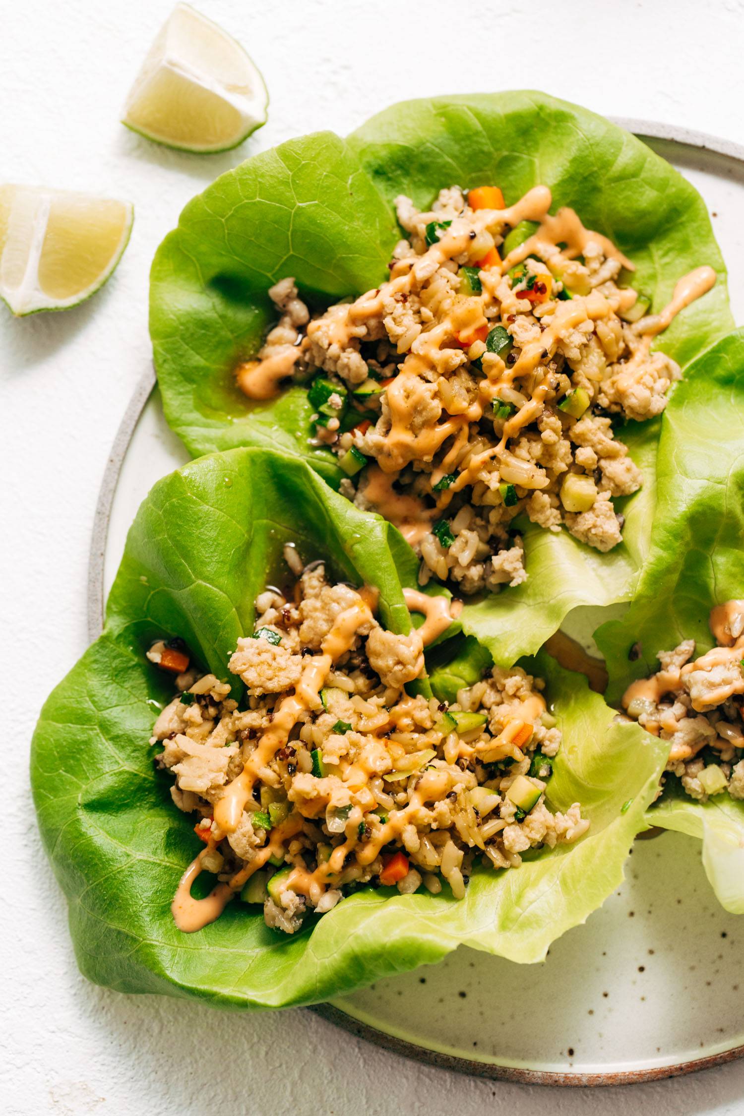 Chicken lettuce wraps set on a table with spicy mayo on top