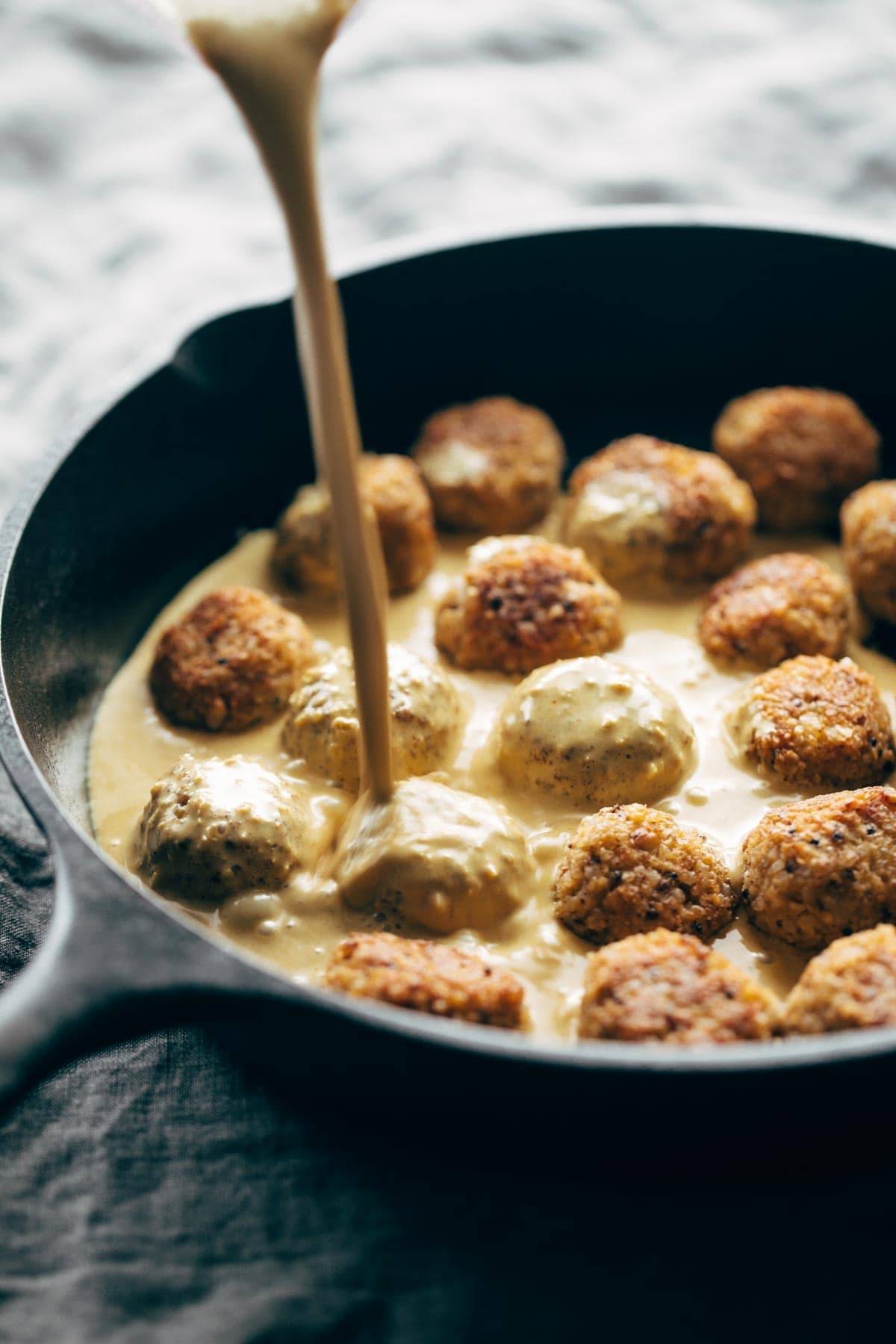 Meatballs in a pan with masala sauce drizzle.