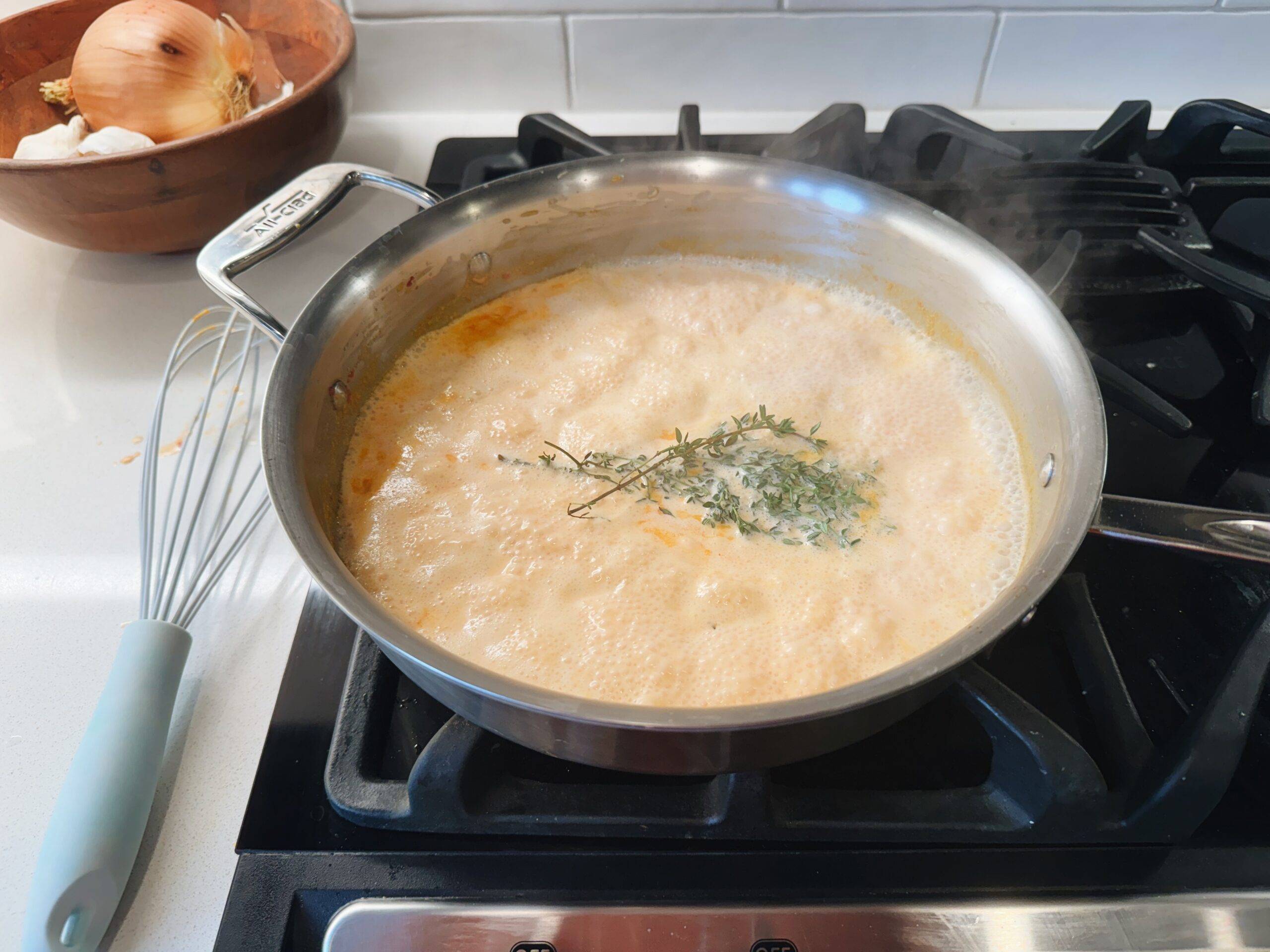 Simmering sauce in a pan with herbs.