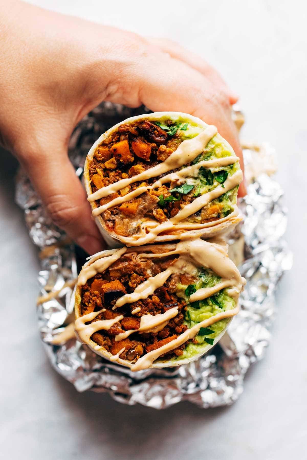 Hand holding vegan mega-burrito.