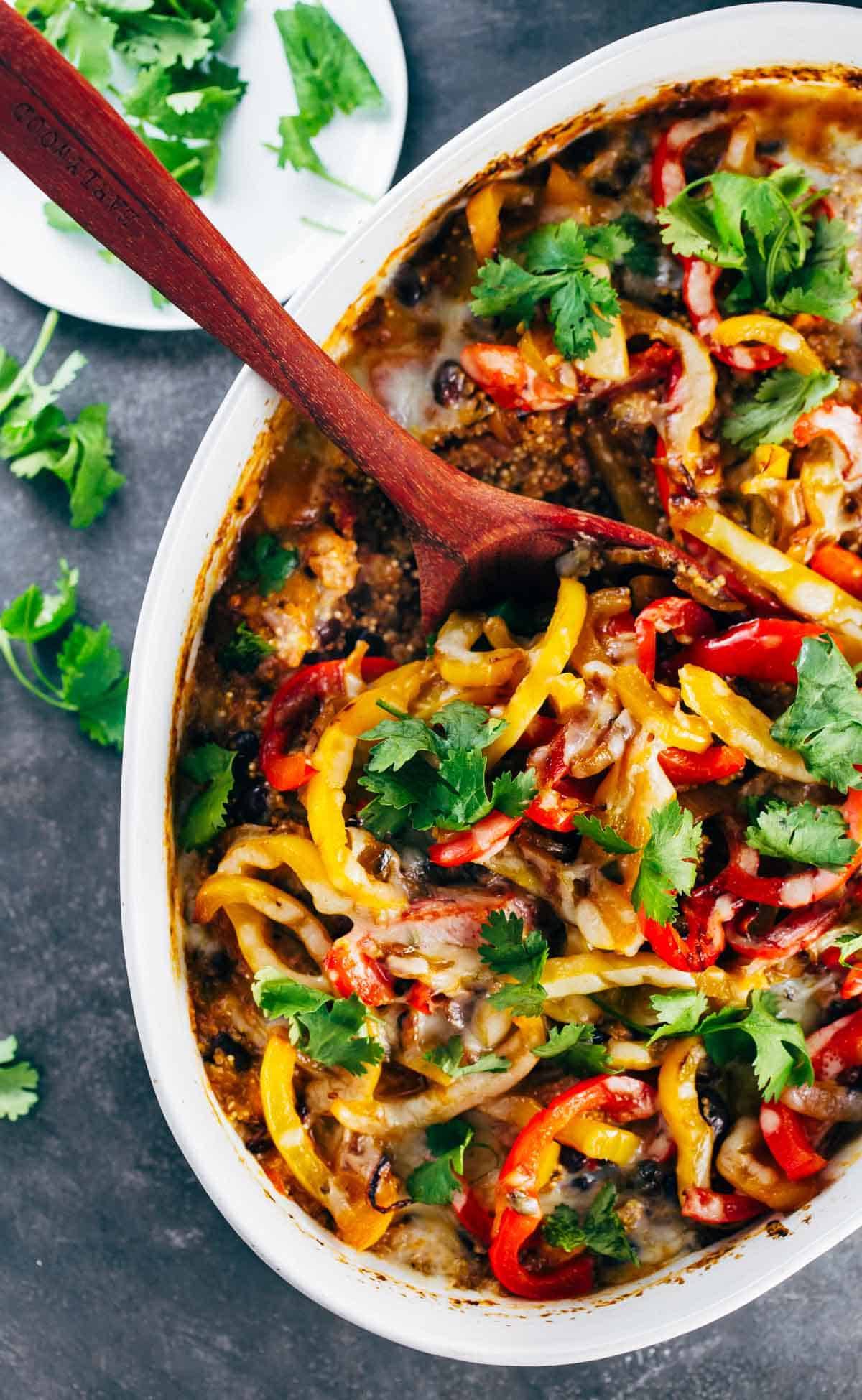 Mexican Chicken Quinoa Casserole in a white baking dish with a wooden spoon.