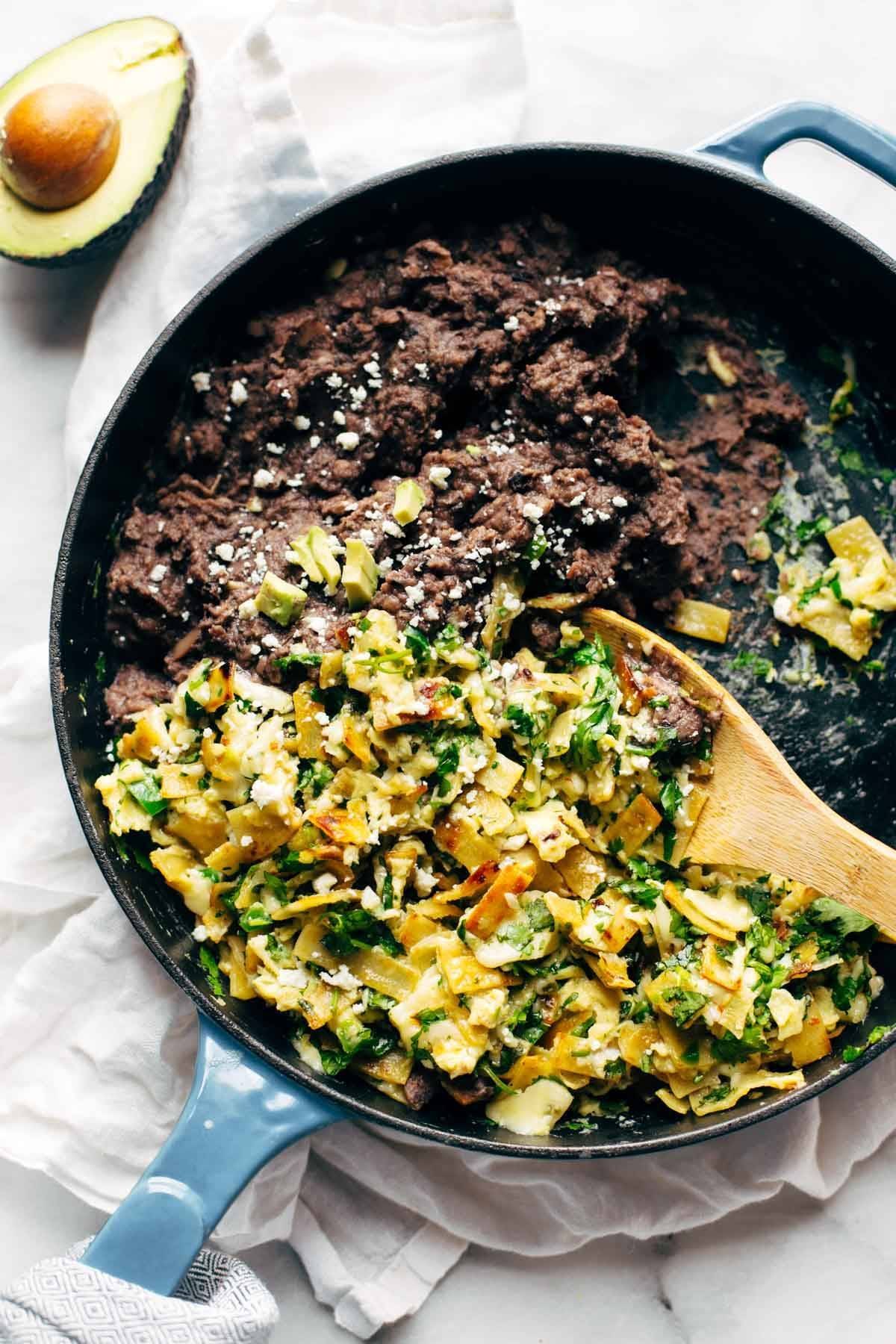 Migas ingredients in a pan with a wooden spoon and an avocado.