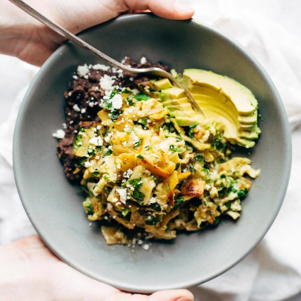 Migas in a bowl with avocado and refried black beans.
