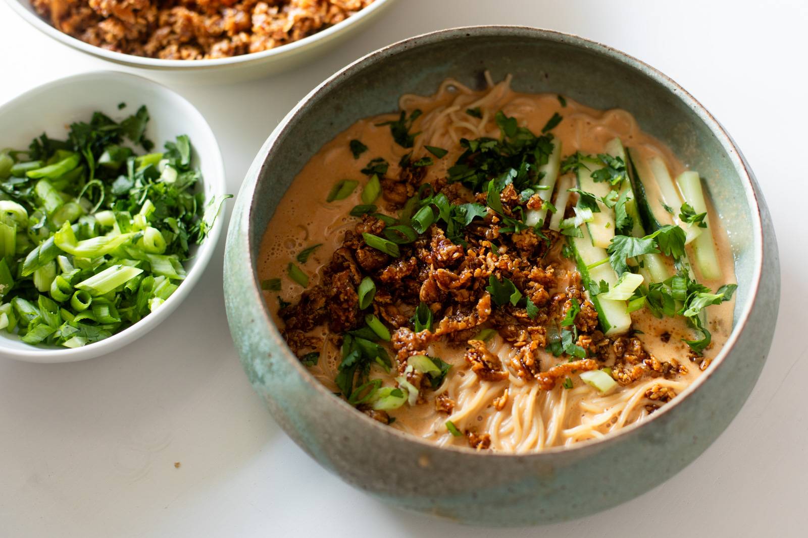 Miso peanut ramen in a bowl with tofu and cucumbers on top.