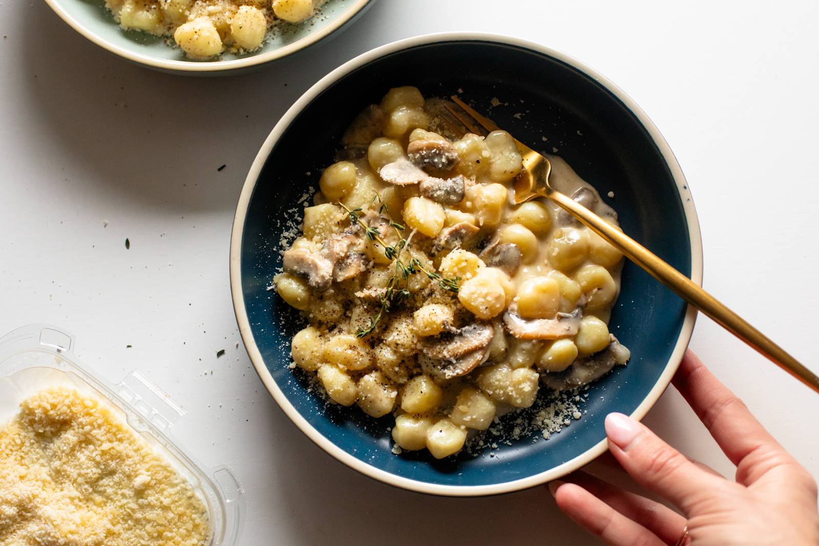 Creamy mushroom gnocchi in a bowl with parmesan sprinkled on top.