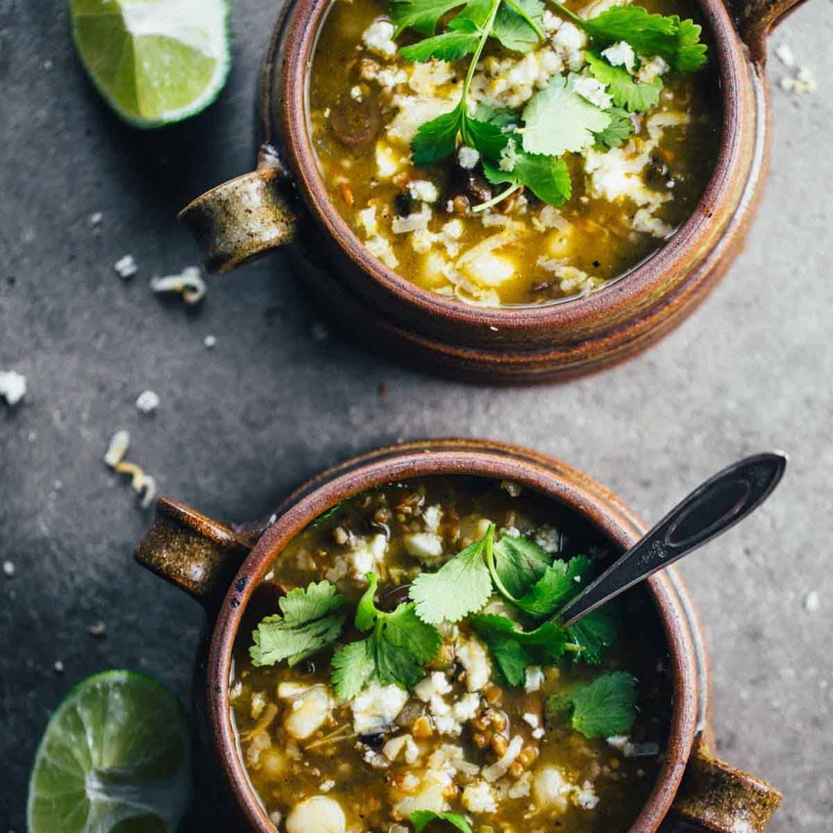 Mushroom Poblano Posole Verde in bowls with a spoon.