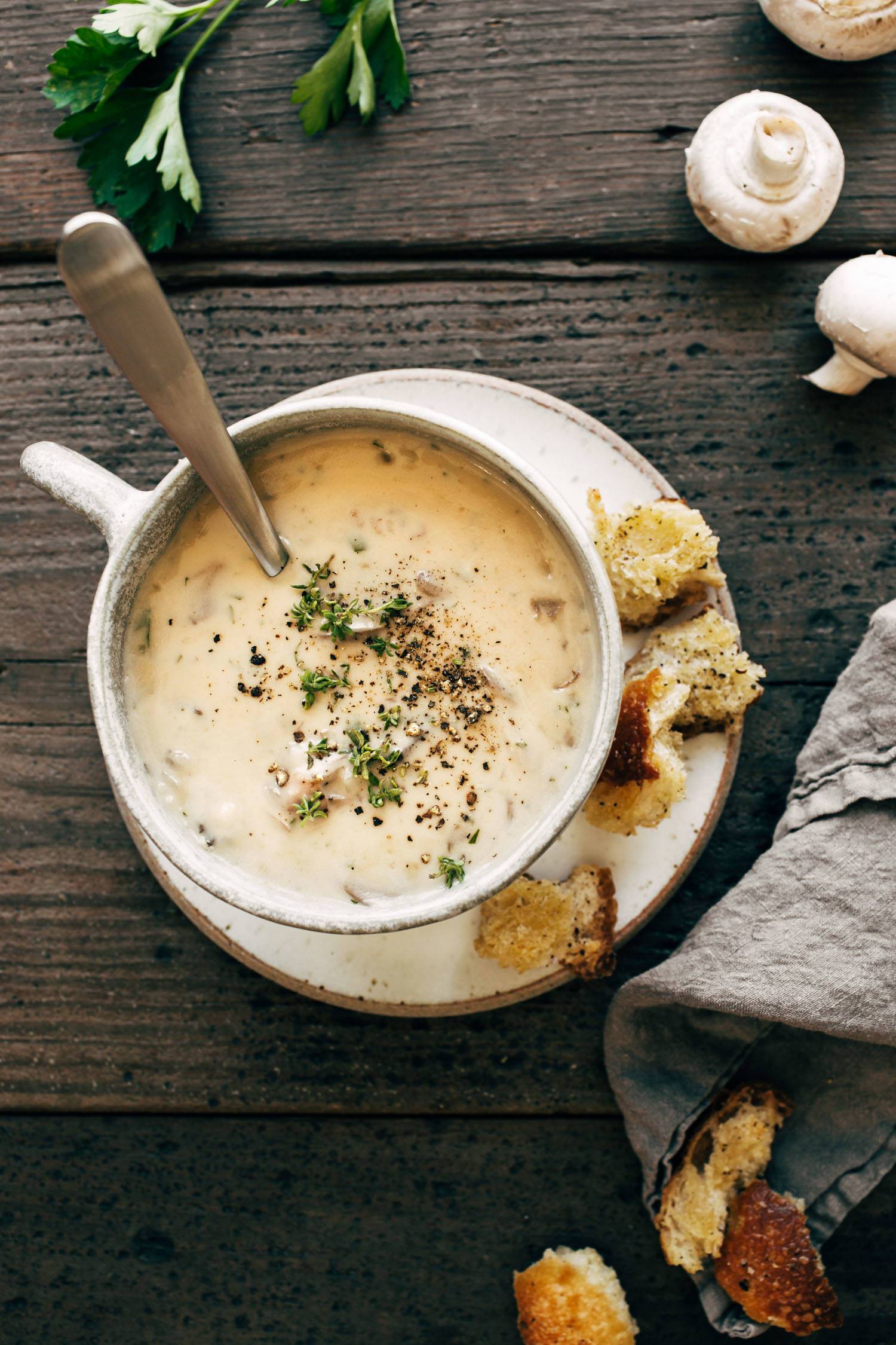 Mushroom soup in a white bowl with croutons on the top and on the side.