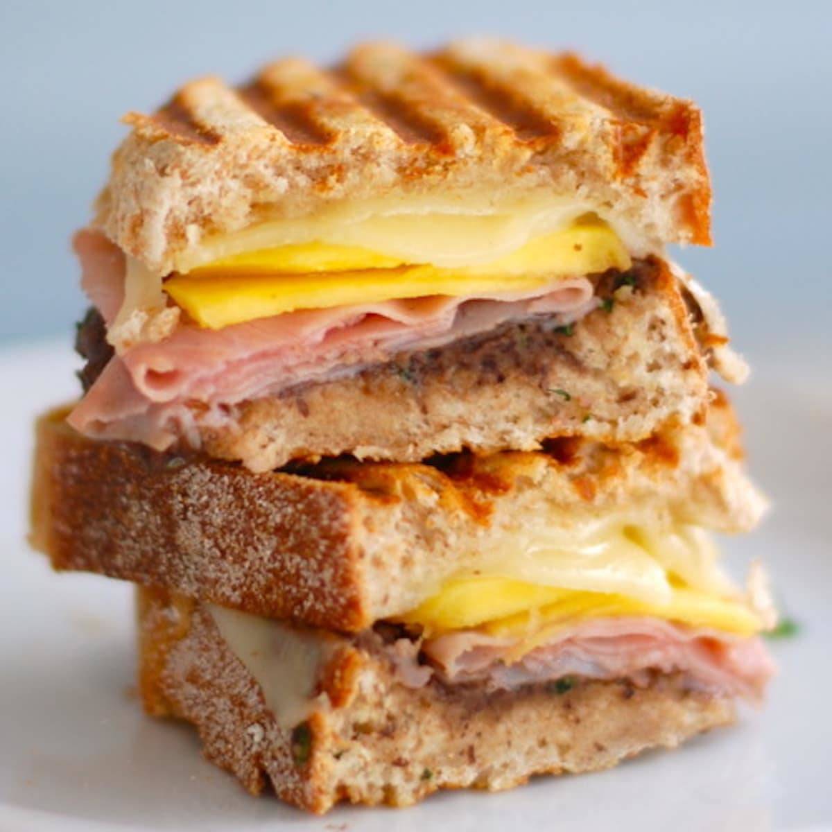 Nuevo cubano sandwich with black bean cilantro puree, sliced mango, ham, and cheese layered between panini grilled bread.