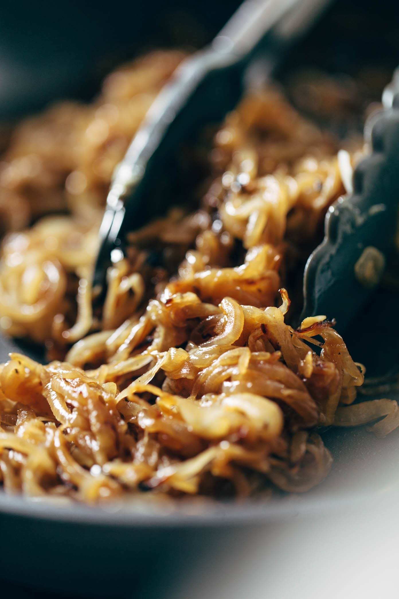 Caramelized Onions in a pan with tongs.