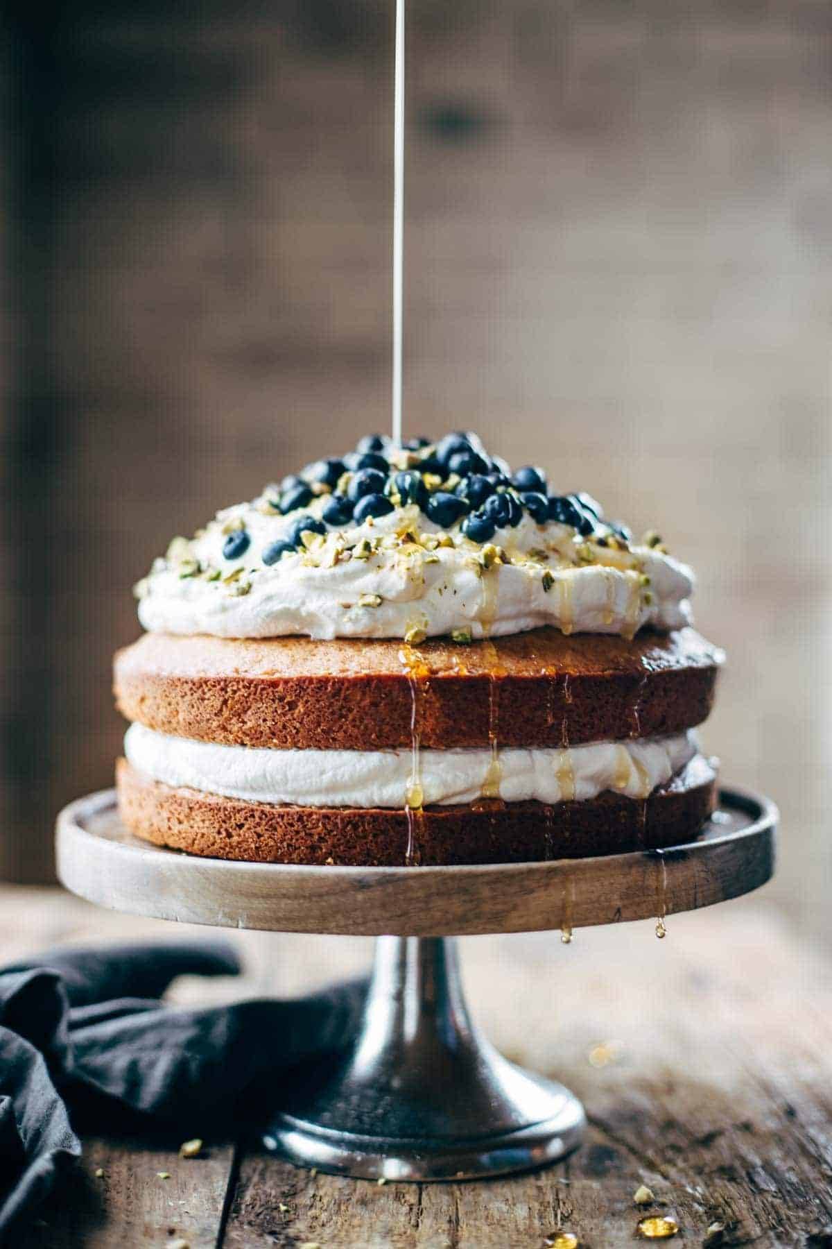 Blueberry orange brunch cake on a cake stand with syrup drizzle.