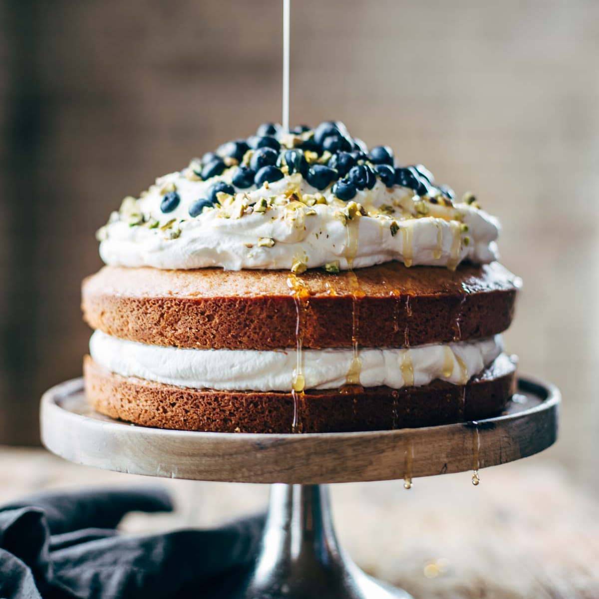 Blueberry Orange Brunch Cake on a cake stand with agave poured on it.